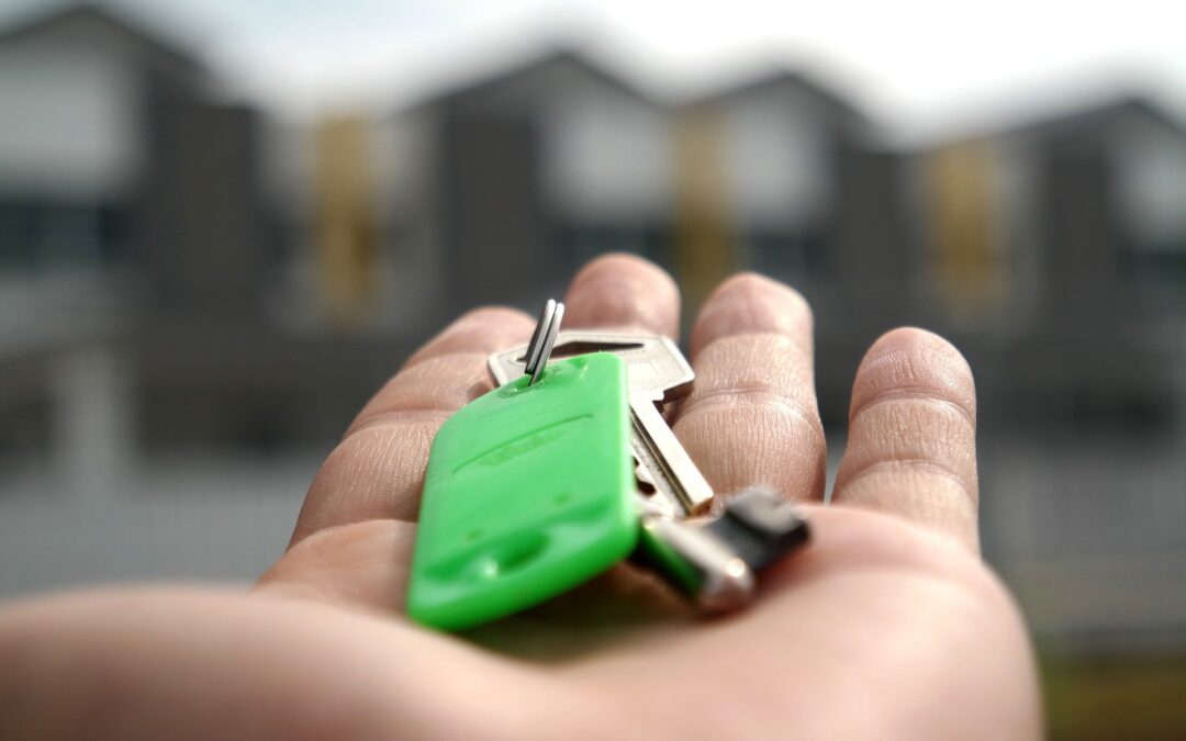 Dłoń trzymająca klucze na tle rozmazanych budynków